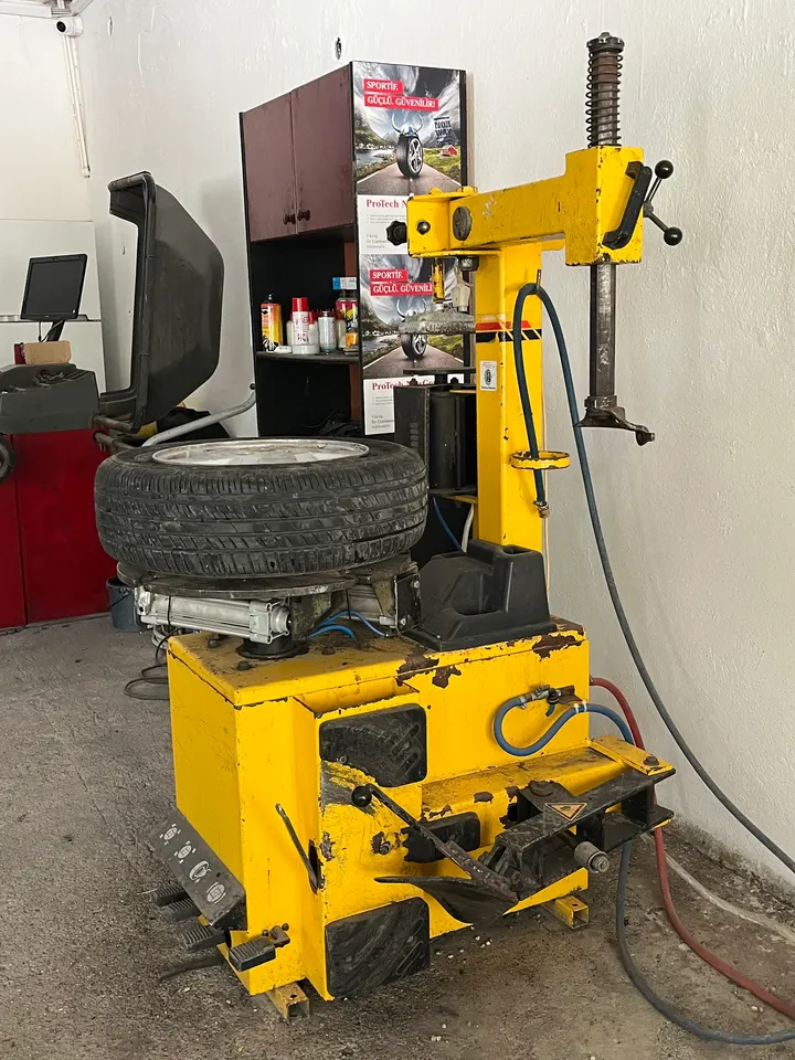 Dükkândaki sarı lastik sökme-takma makinesi ve jant çalışma istasyonu