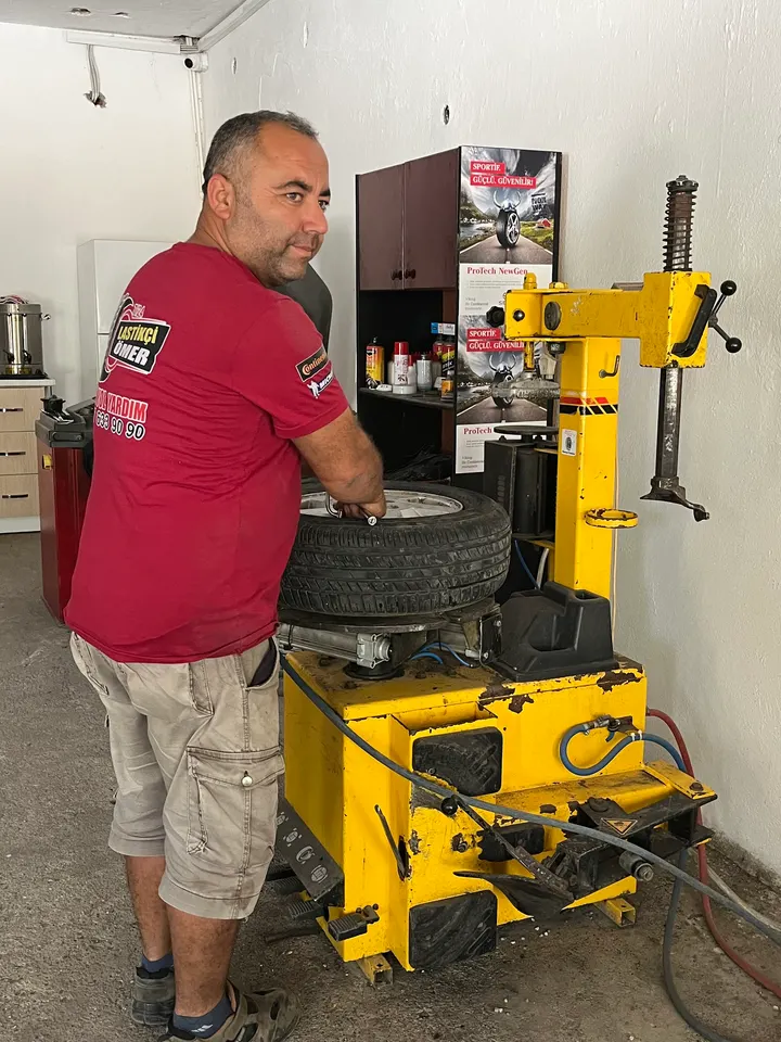 Lastikçi Ömer dükkândaki lastik sökme-takma makinesinde bir lastiği jantından ayırıyor