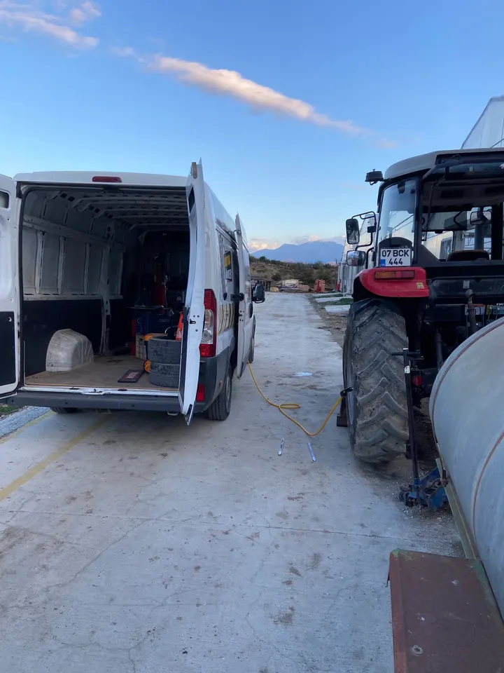 Mobil servis aracı bir traktörün yanına yanaşmış, sahada lastik değişimi yapılıyor